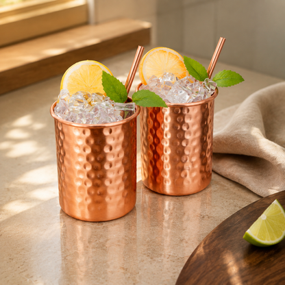 Two hammered copper mugs with two matching copper straws