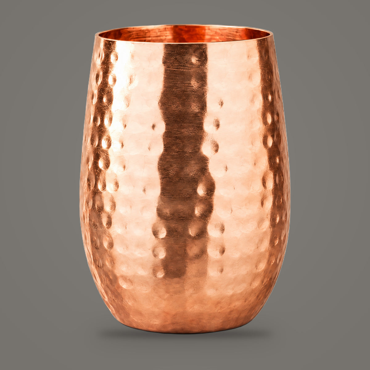Hammered copper cocktail cup on a plain mid grey background