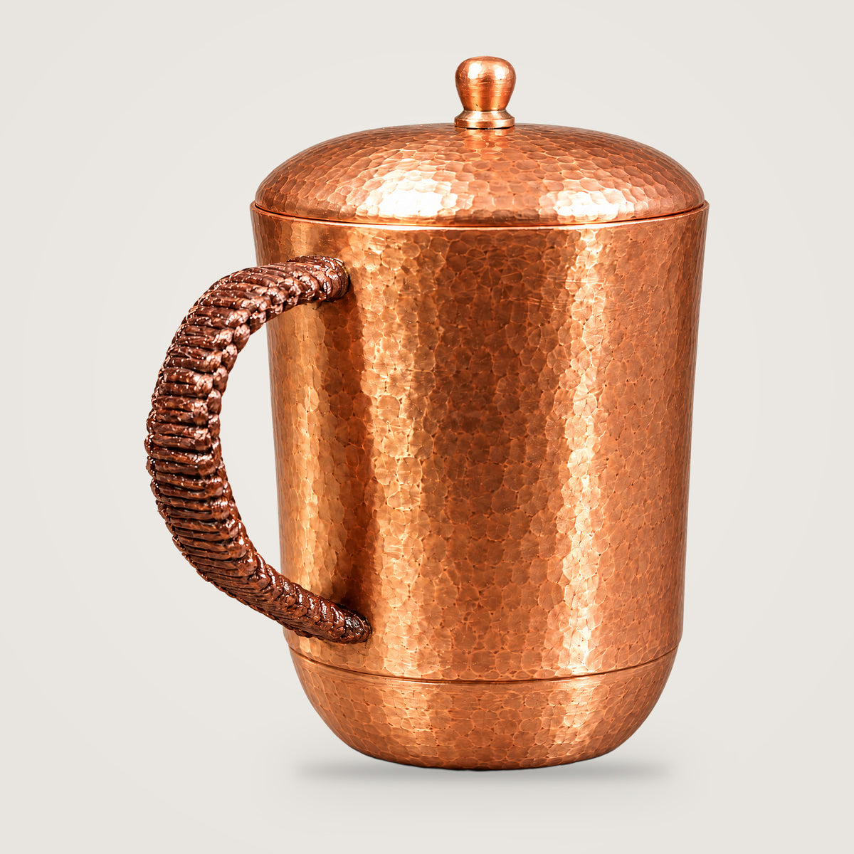 Hammered copper water tumbler on a plain light grey background