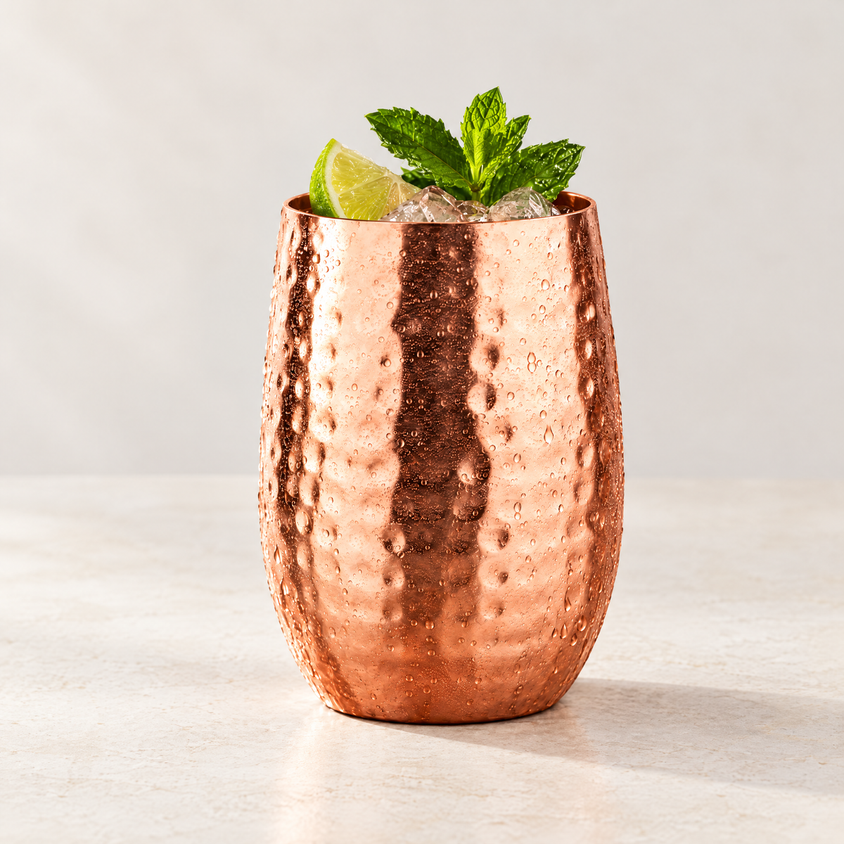Hammered copper cocktail cup served with ice, lime and mint