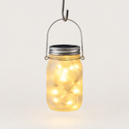Solar mason jar lantern hanging from its wire handle, lit