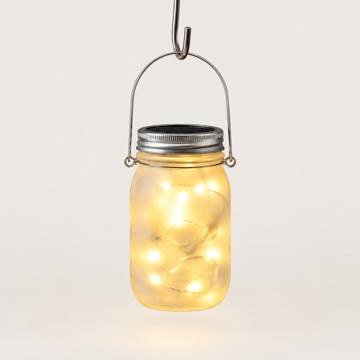 Solar mason jar lantern hanging from its wire handle, lit