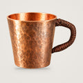 Woven-handle copper espresso cup on a plain light grey background